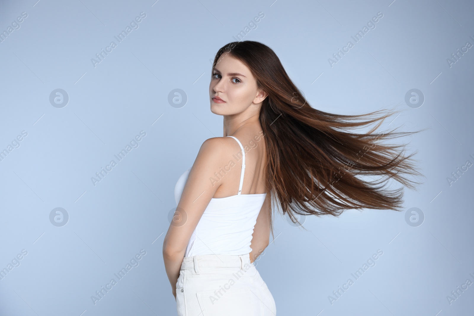 Photo of Young woman with strong healthy hair on light blue background