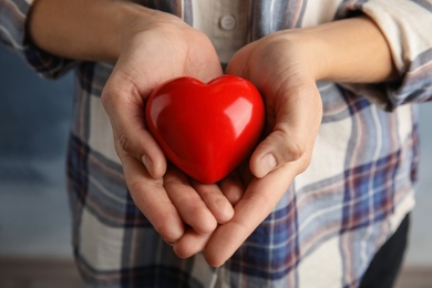 Woman holding red heart in hands, closeup. Helping and supporting concept