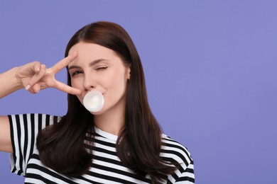 Beautiful woman blowing bubble gum and gesturing on light purple background, space for text