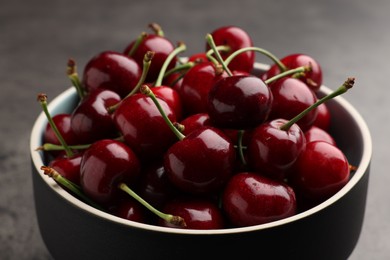 Photo of Bowl with ripe sweet cherries on dark grey table, closeup