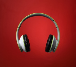 Stylish modern headphones with earmuffs on color background