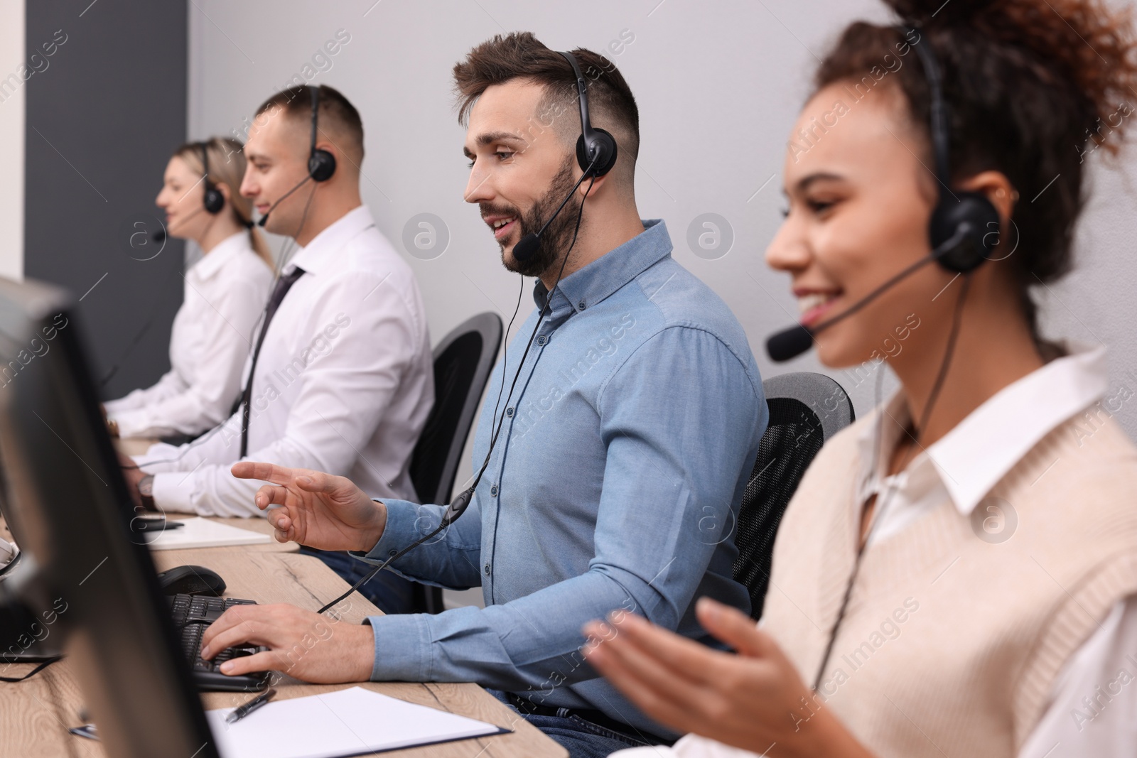 Photo of Call center operators working in modern office, focus on man with headset
