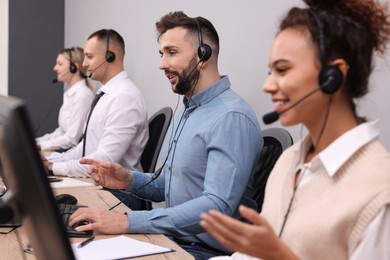 Call center operators working in modern office, focus on man with headset