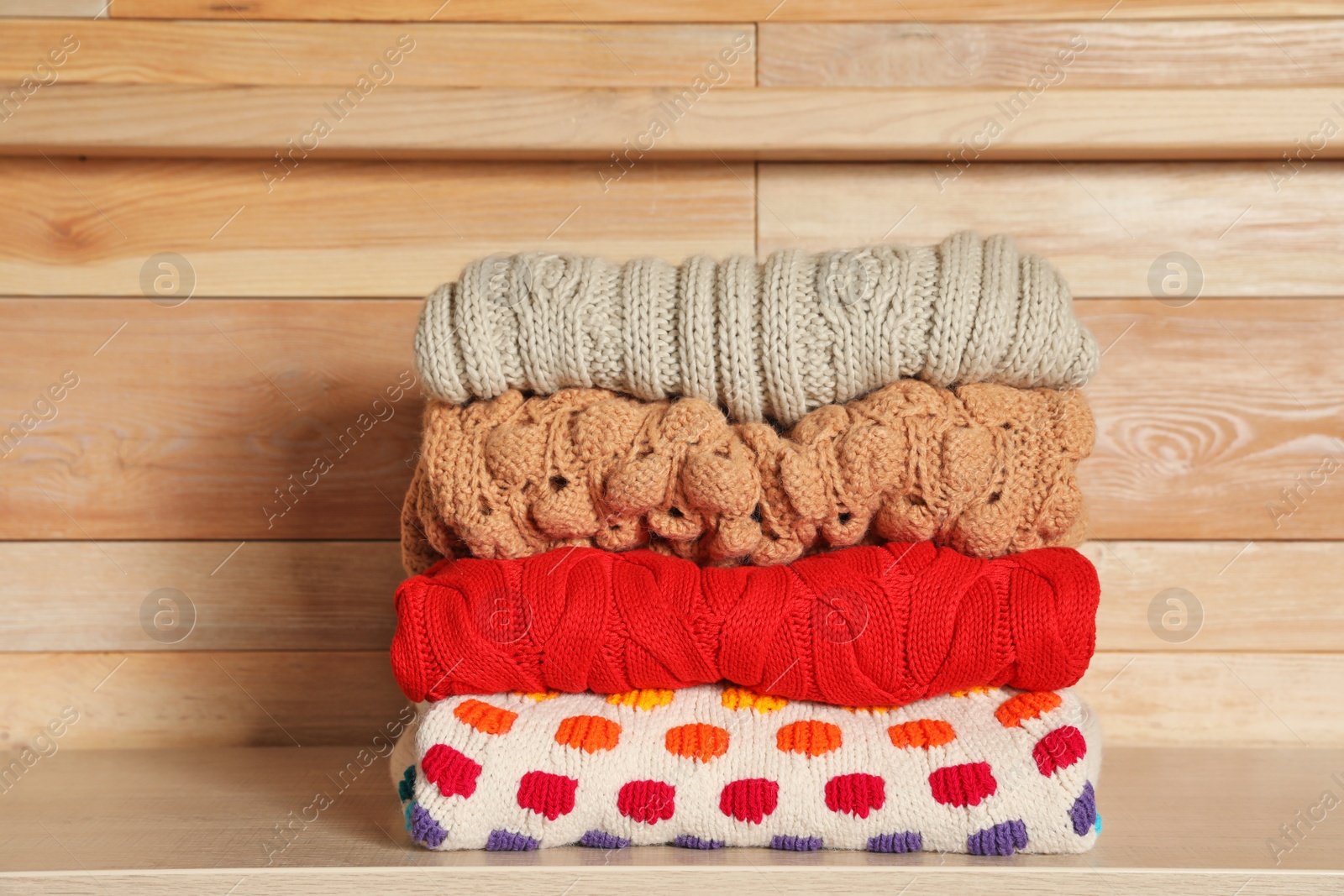 Photo of Stack of winter clothes against wooden background