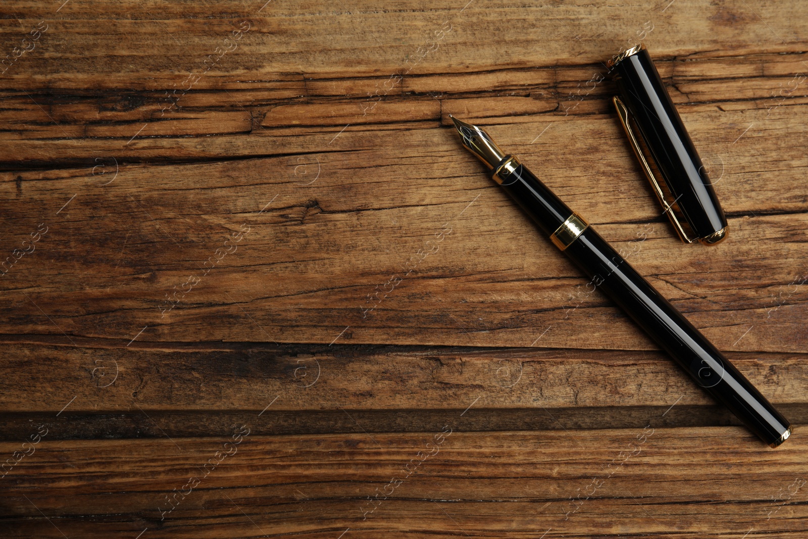 Photo of Beautiful fountain pen on wooden table, flat lay. Space for text