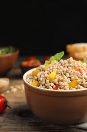 Tasty buckwheat porridge with vegetables on wooden table, closeup. Space of text