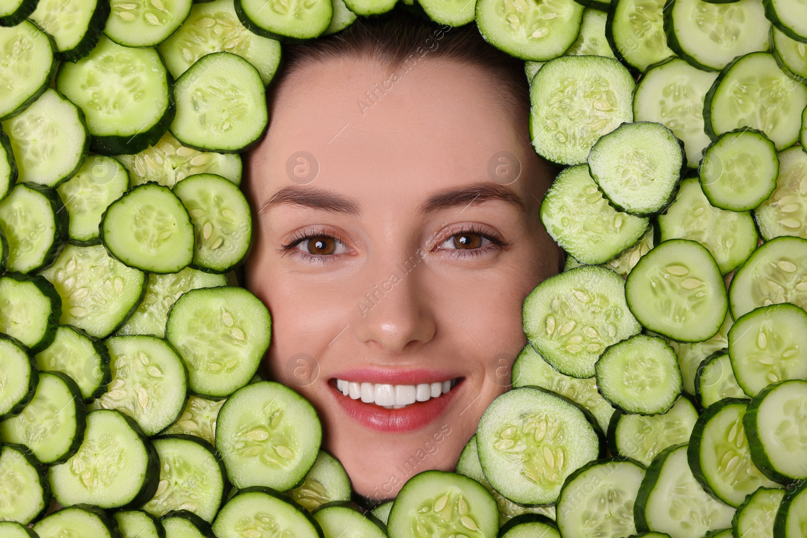 Photo of Beautiful woman among cucumber slices, top view