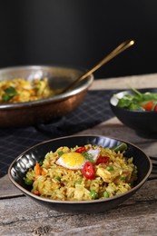 Photo of Tasty rice with meat, egg and vegetables in bowl on wooden table