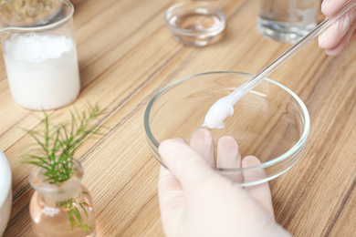 Photo of Scientist developing cosmetic product at wooden table in laboratory, closeup