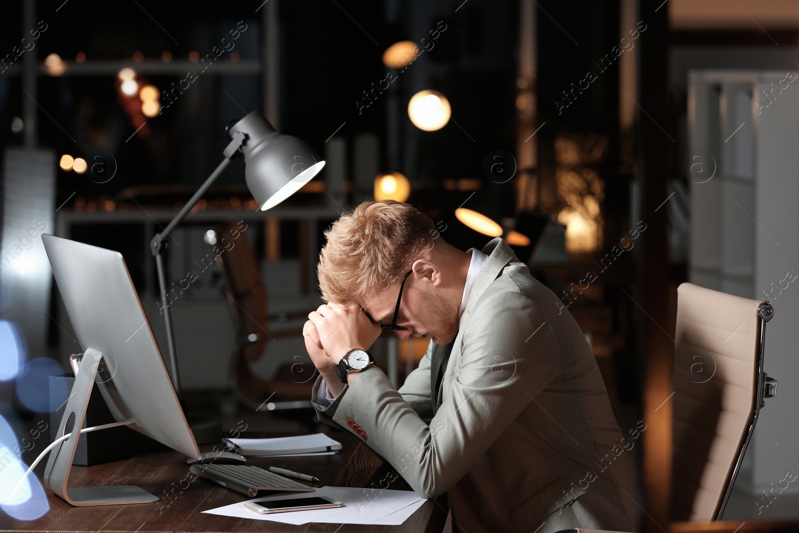 Photo of Tired young businessman working in office alone at night