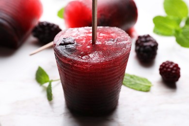 Photo of Tasty blackberry ice pops on white marble table, closeup. Fruit popsicle