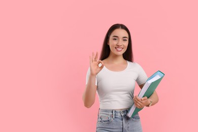 Photo of Happy woman with folder showing OK gesture on pink background, space for text
