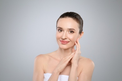 Portrait of beautiful young woman with perfect skin on grey background. Spa treatment