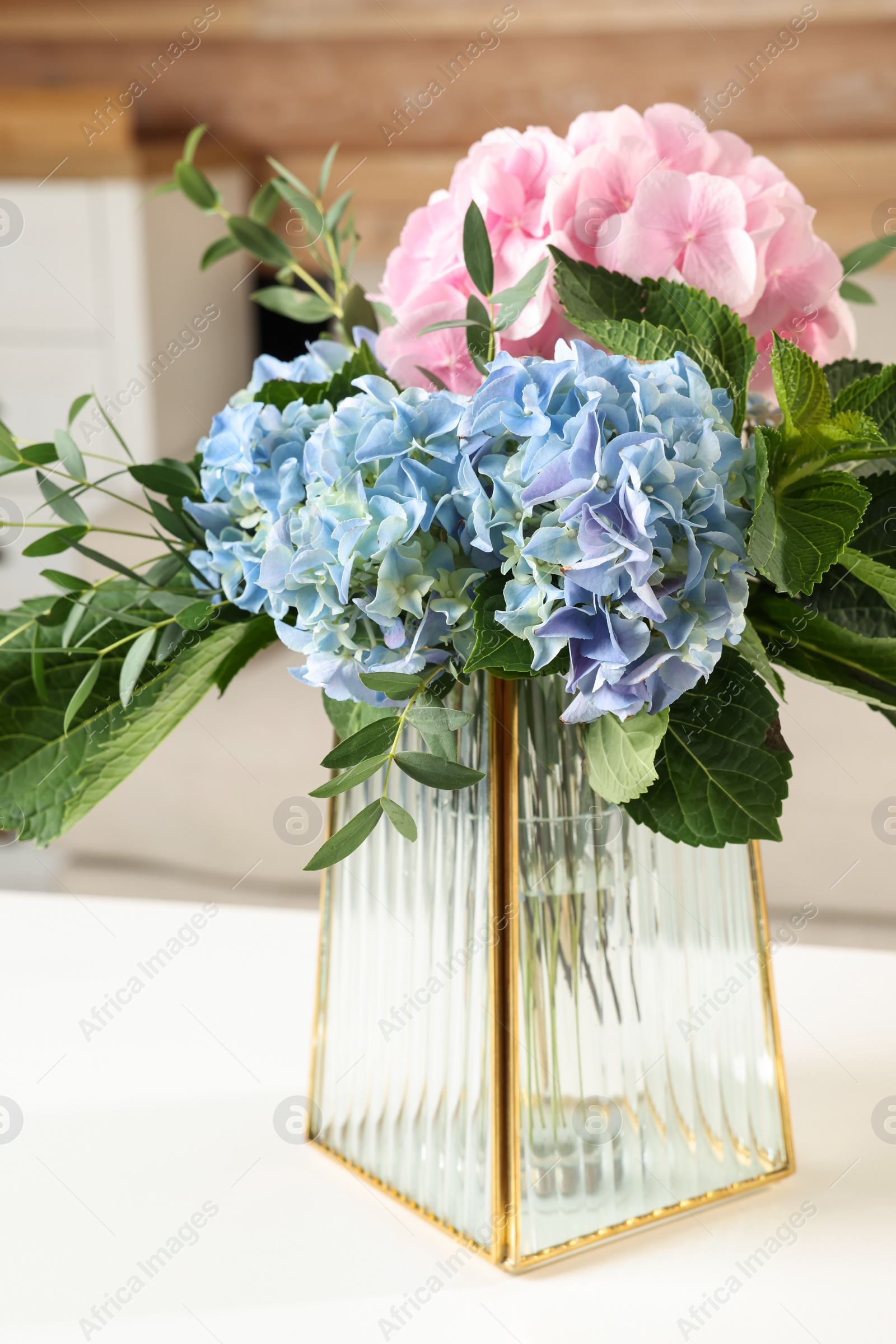 Photo of Beautiful hortensia flowers in vase on white table indoors
