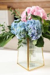 Photo of Beautiful hortensia flowers in vase on white table indoors