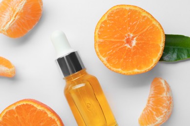 Photo of Aromatic tangerine essential oil in bottle and citrus fruits on white table, flat lay