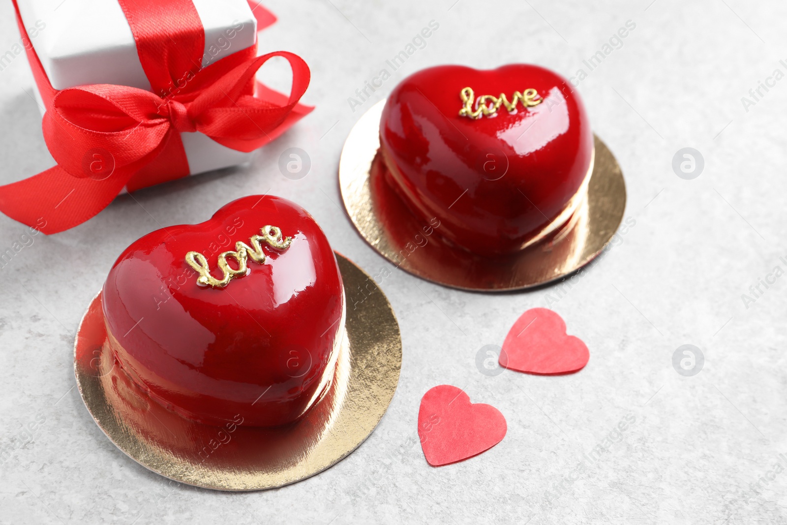 Photo of St. Valentine's Day. Delicious heart shaped cakes and gift on light table, closeup