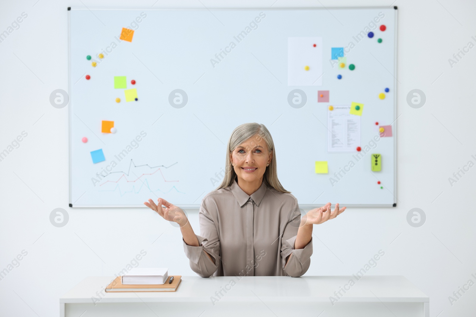 Photo of Happy professor giving lecture at desk in classroom