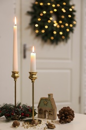Photo of Christmas composition with burning candles on table in room