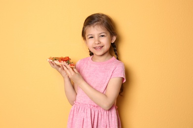 Photo of Cute little girl with slice of pizza on color background