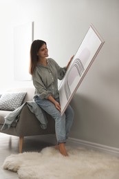Photo of Woman holding picture near wall in room. Interior design