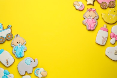 Photo of Cute tasty cookies of different shapes on yellow background, flat lay with space for text. Baby shower party