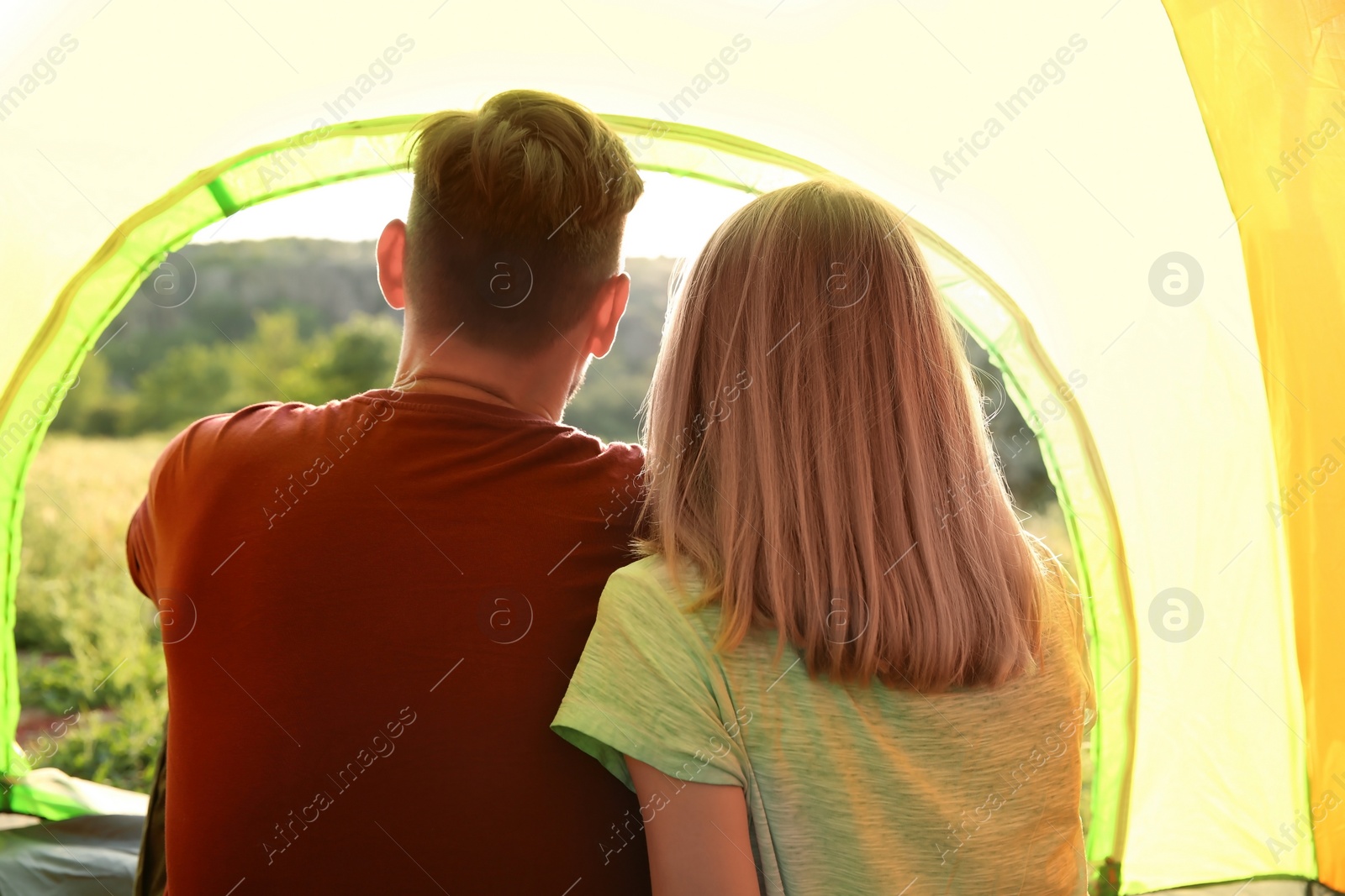 Photo of Young couple resting in camping tent, view from inside