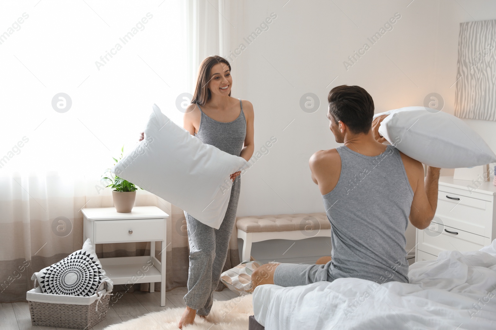 Photo of Happy young couple having pillow fight in bedroom