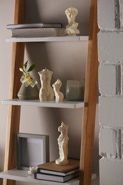 Photo of Beautiful David bust and body shaped candles on rack indoors