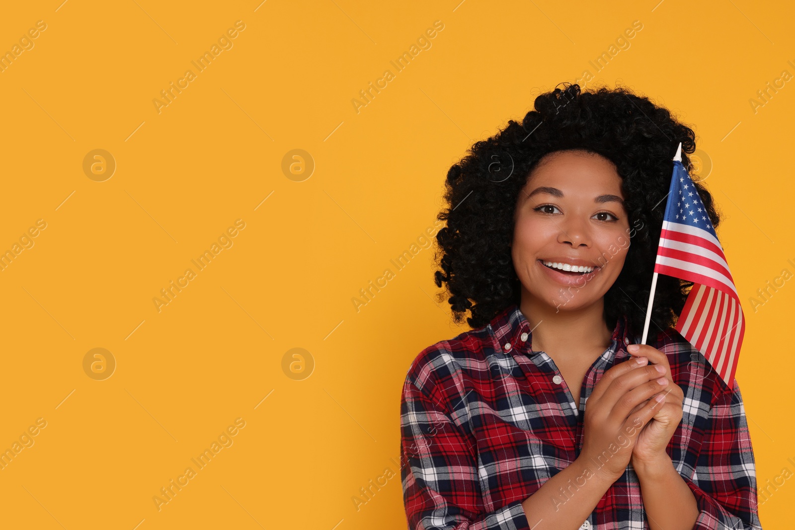 Photo of 4th of July - Independence Day of USA. Happy woman with American flag on yellow background, space for text