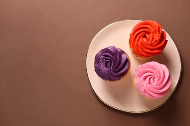 Photo of Delicious cupcakes with bright cream on brown background, top view. Space for text