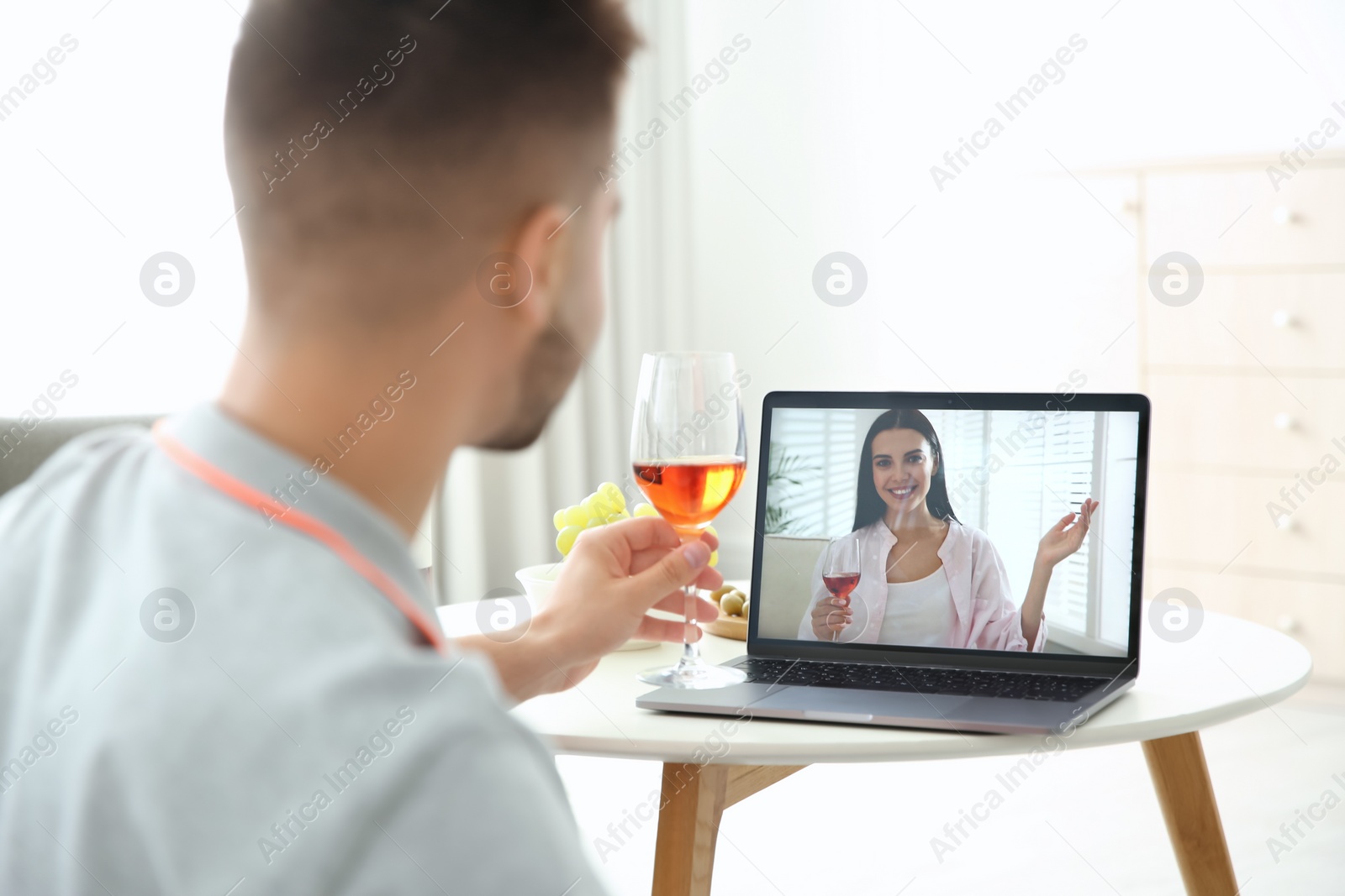 Photo of Friends drinking wine while communicating through online video conference at home. Social distancing during coronavirus pandemic