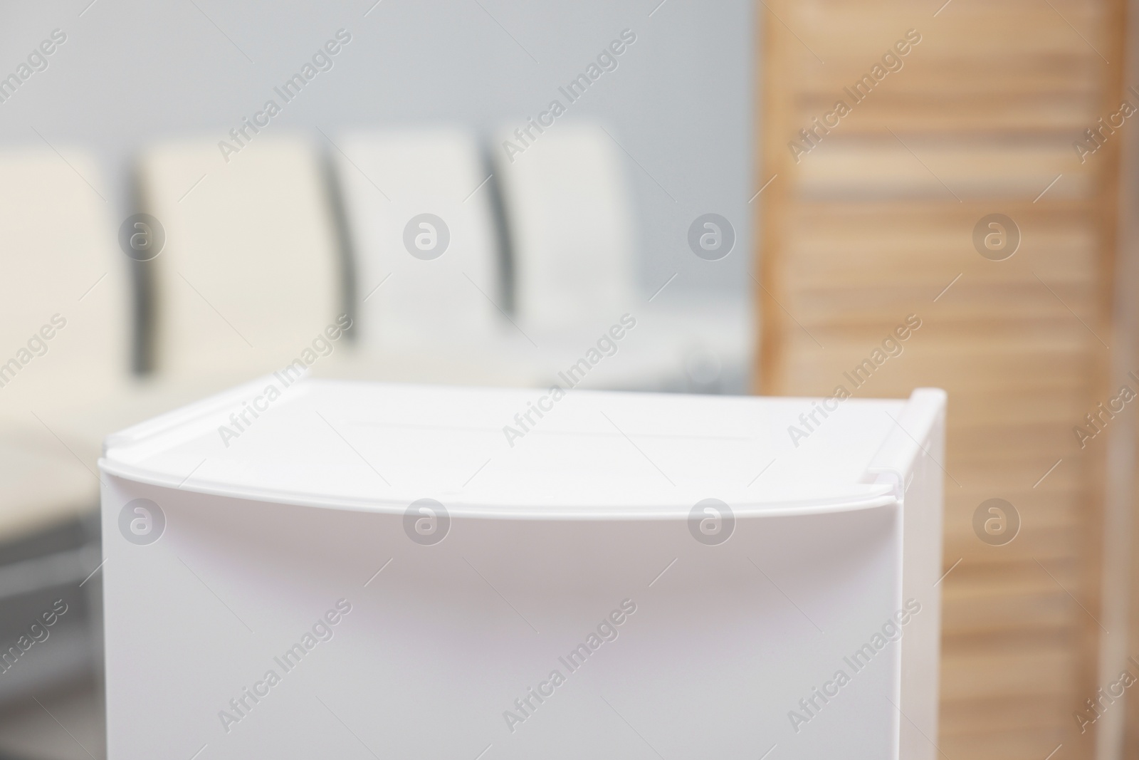 Photo of White ballot box on blurred background, closeup. Space for text