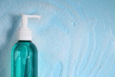 Photo of Bottle of cosmetic product and foam on light blue background, top view. Space for text