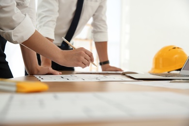 Photo of People working with construction drawings at table, closeup