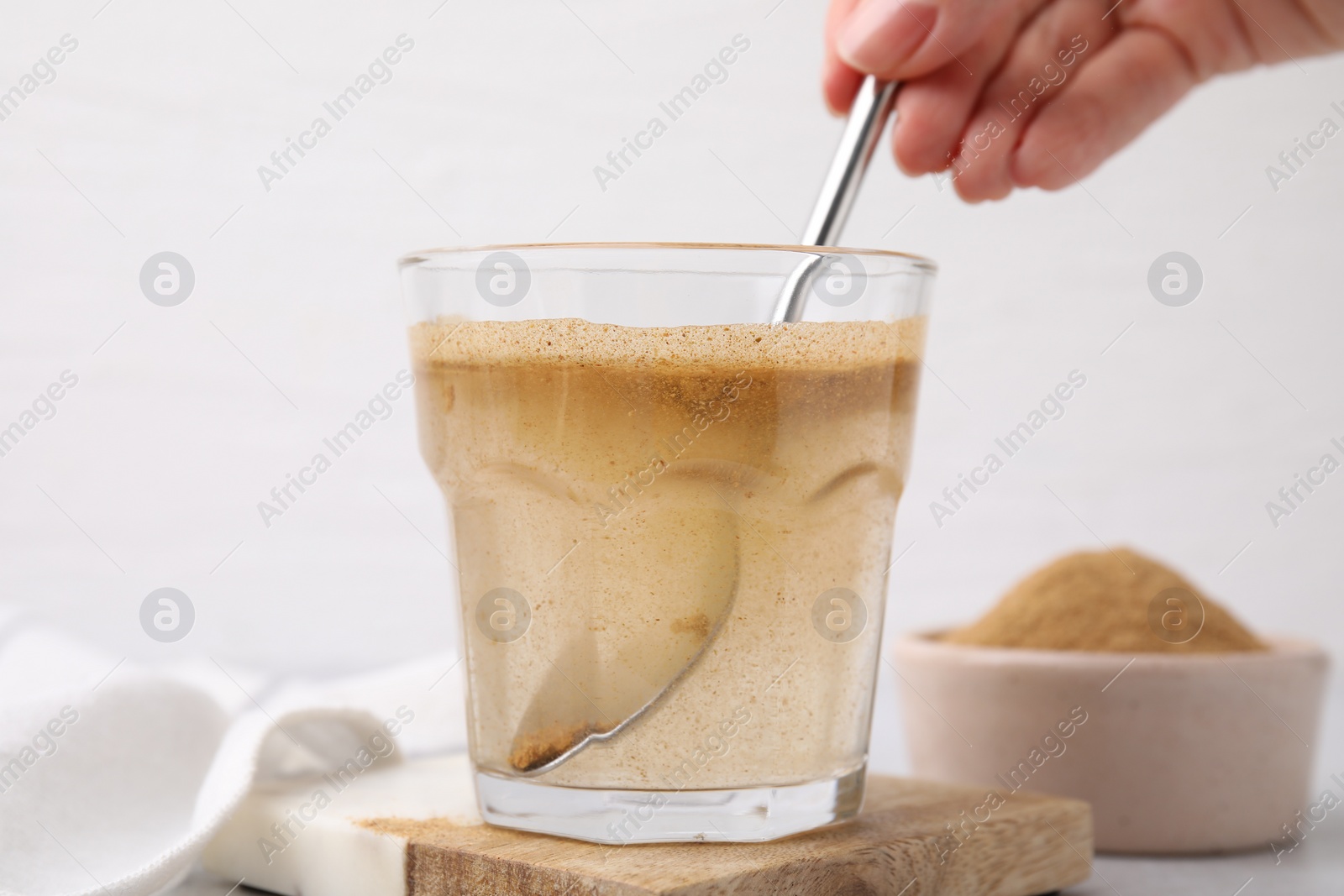 Photo of Dietary fiber. Woman stirring psyllium husk powder in water at table, closeup