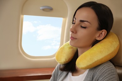 Photo of Young woman with travel pillow sleeping in airplane during flight