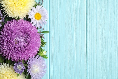 Photo of Flat lay composition with beautiful aster flowers on light blue wooden table. Space for text