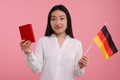 Immigration to Germany. Woman with passport and flag on pink background