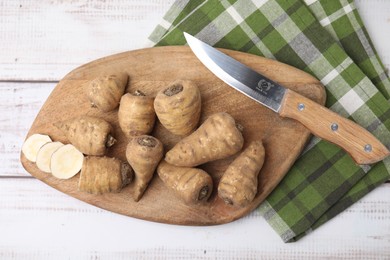 Photo of Turnip rooted chervil tubers and knife on light wooden table, top view