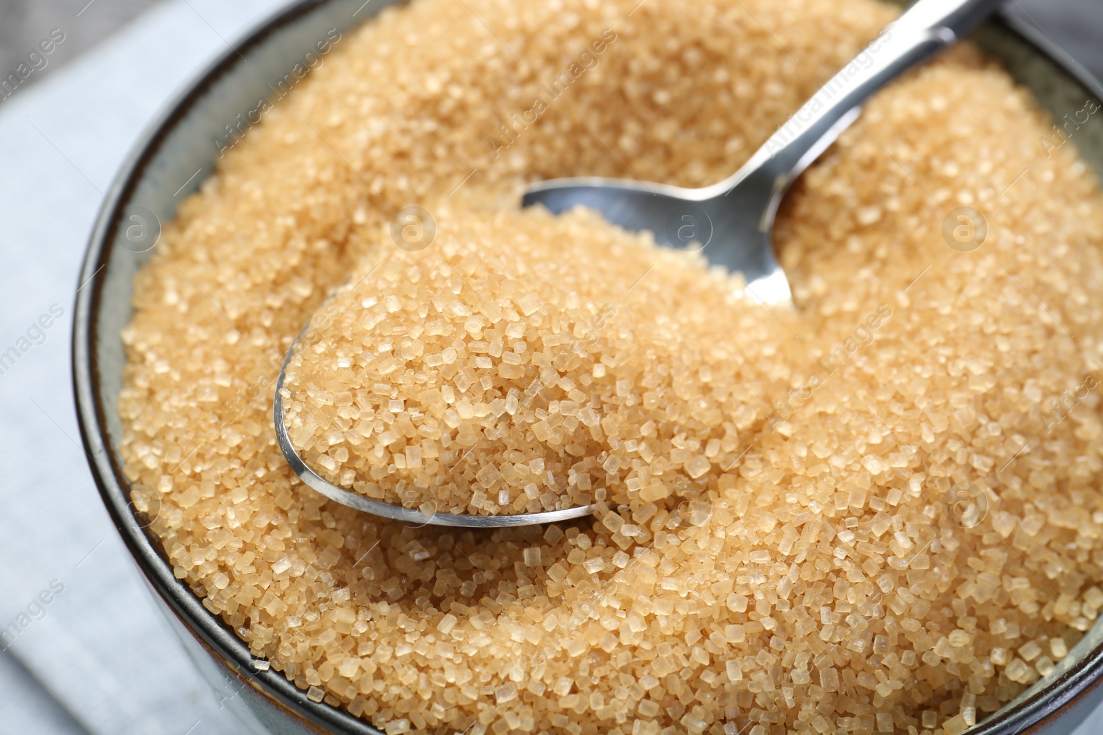 Photo of Brown sugar in bowl and spoon on table, closeup