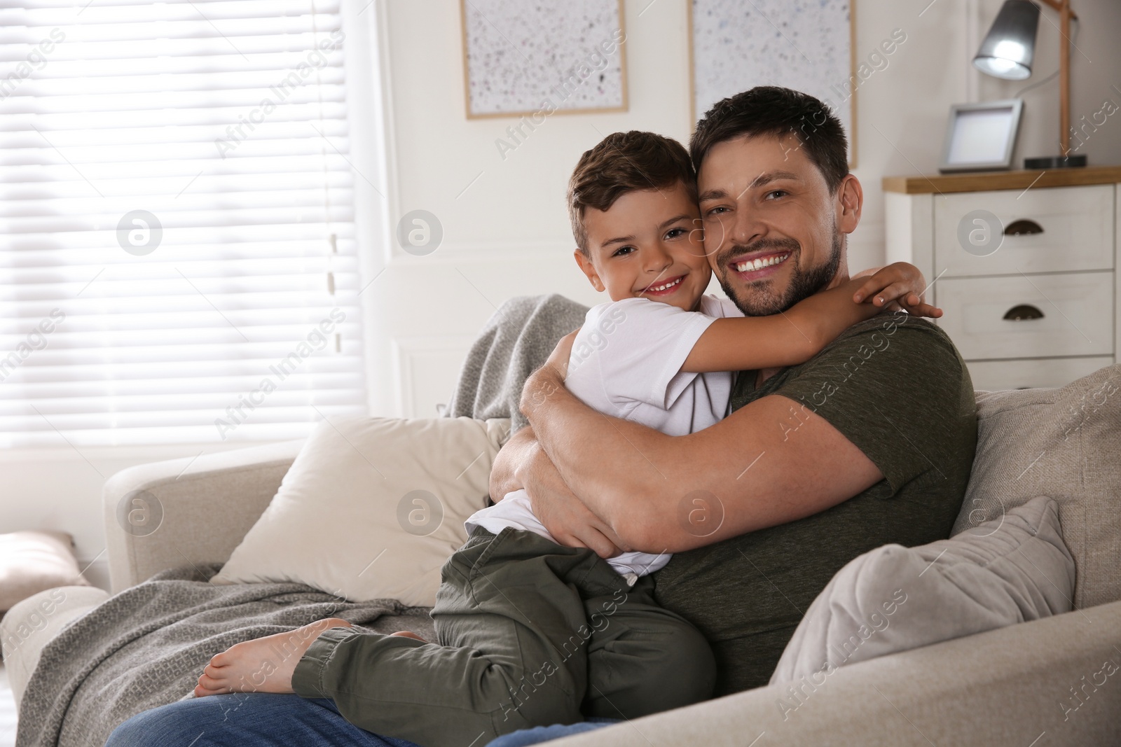 Photo of Father and his son on sofa in living room. Adoption concept