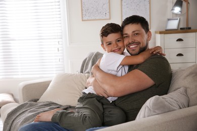 Father and his son on sofa in living room. Adoption concept