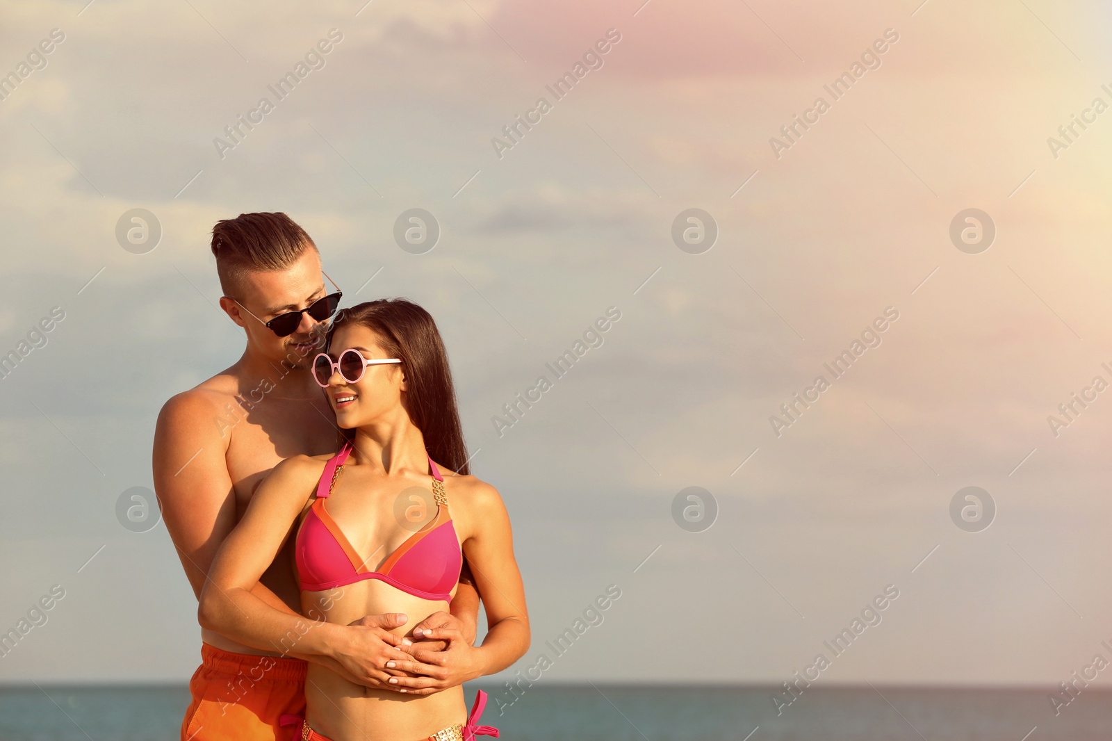 Photo of Young woman in bikini spending time with her boyfriend on beach. Lovely couple