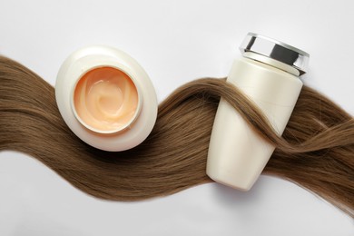 Photo of Natural cosmetic products and hair lock on white background, flat lay