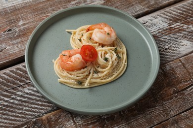 Photo of Heart made of tasty spaghetti, tomato, shrimps and cheese on wooden table