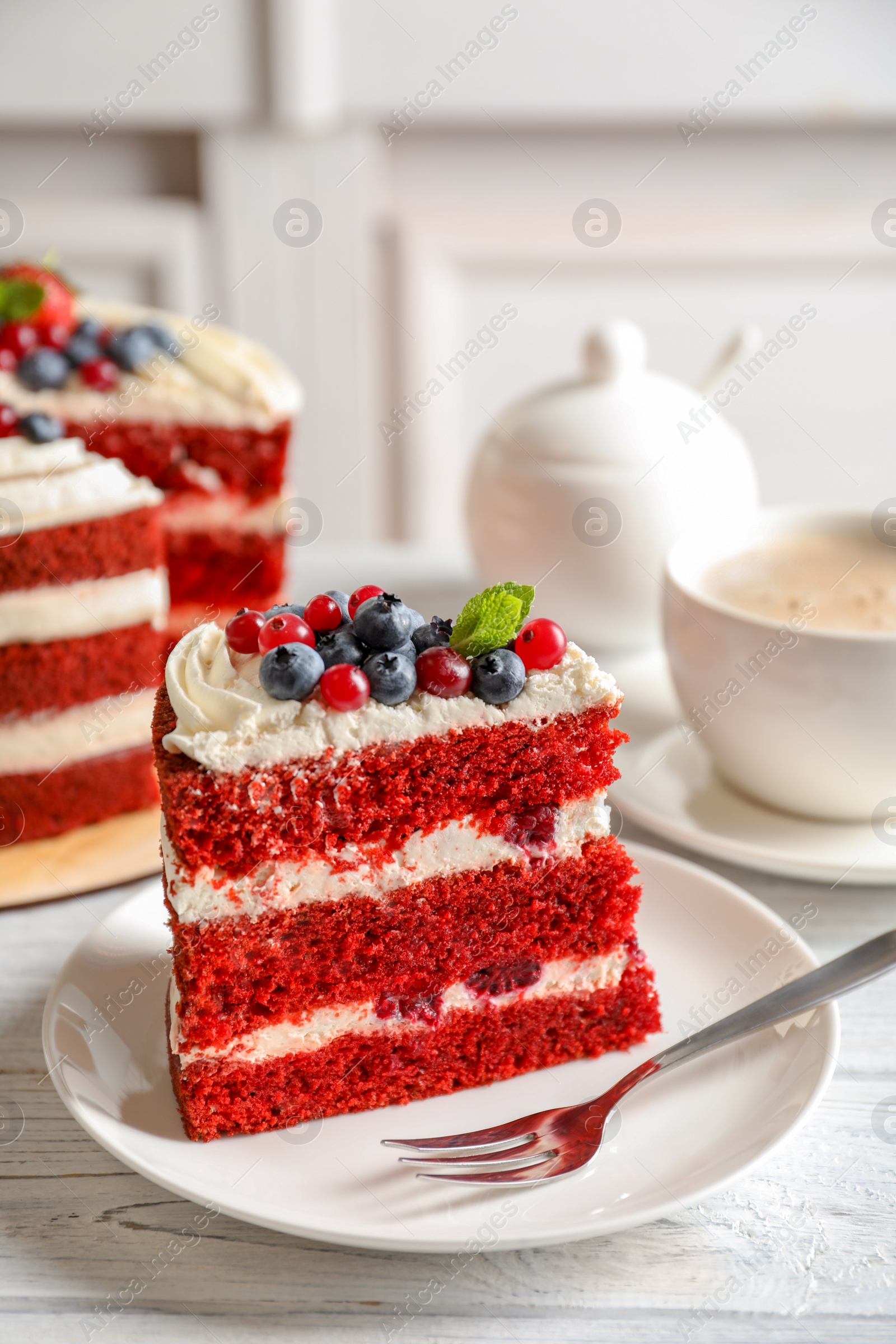 Photo of Plate with piece of delicious homemade red velvet cake on table