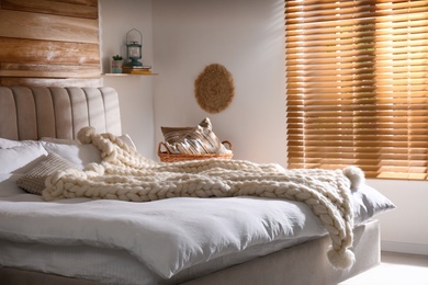 Bed with white knitted plaid in room. Interior design