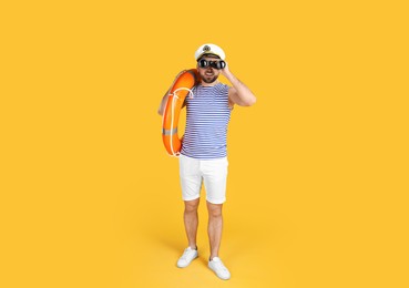 Sailor with binoculars and ring buoy on yellow background
