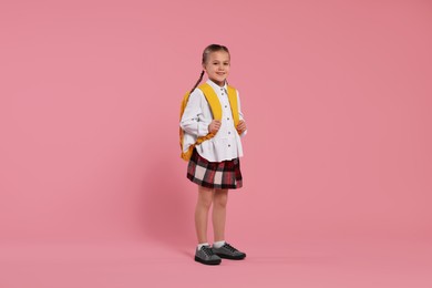 Photo of Happy schoolgirl with backpack on pink background